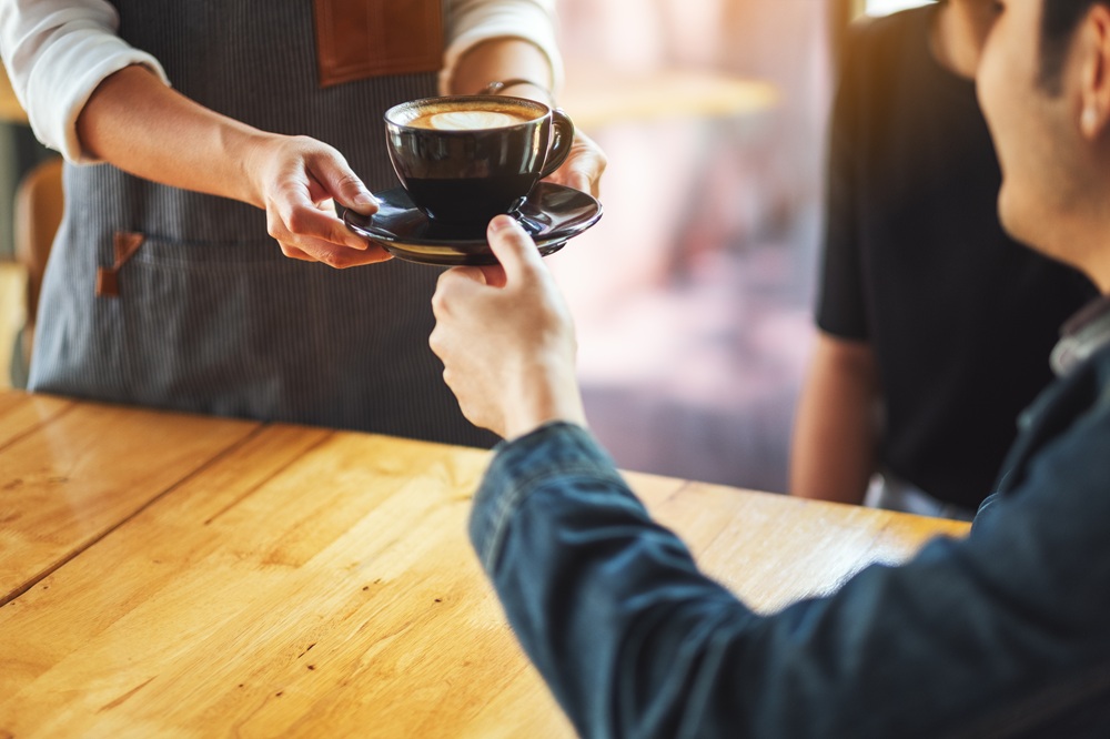 Kellner serviert Kaffee in einem Cafe
