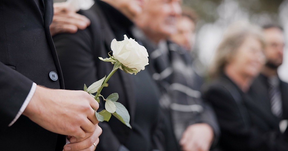 Blume in der hand einer trauernden Person