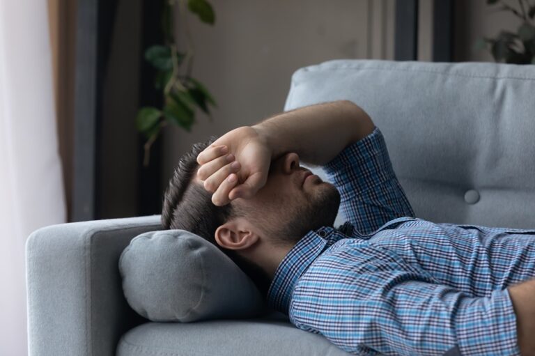 Mann liegt erschöpft auf dem Sofa