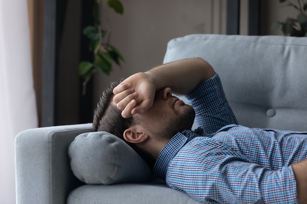 Mann liegt erschöpft auf dem Sofa